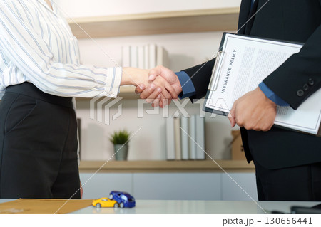 Insurance Agreement. Client and agent shaking hands after signing policy. Insurance Agreement. Client and agent shaking hands after signing policy. 130656441