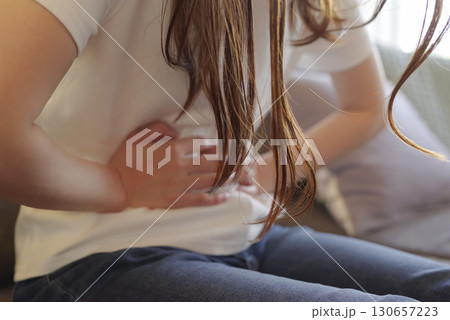 お腹を押さえる女性の腹痛イメージ 130657223