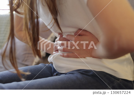 お腹を押さえる女性の腹痛イメージ 130657224