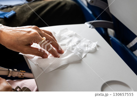 Air travel passenger wiping airplane table with anti-bacterial wet wipes Air travel passenger wiping airplane table with anti-bacterial wet wipes 130657555