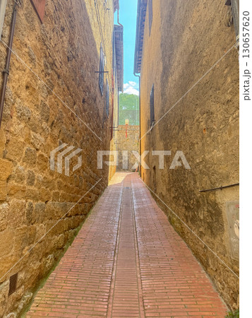 Narrow stone alleyway with quaint brick path leading through historic village. Rustic charm of ancient architecture creates a serene and timeless passageway. Ideal for travel themes. Italy, San 130657620