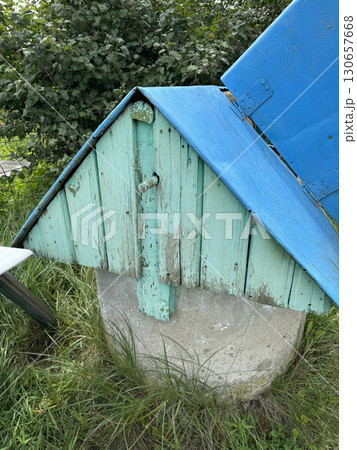 Well in a village. House-shaped lid over a mine shaft well. 130657668