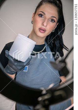 Beautician woman in black gloves holding jar of sugaring paste for hair removal procedure 130657781