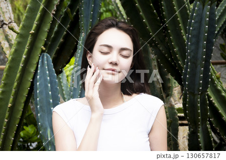 サボテンの前に立つきれいな女性 130657817