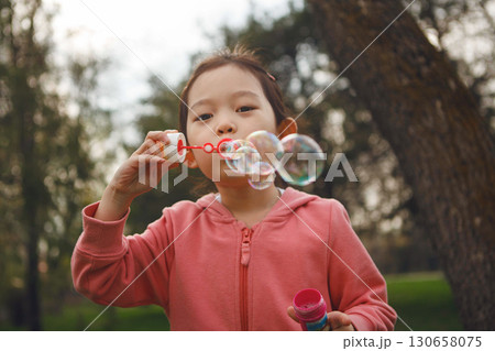 Girl Blowing Bubbles in Park Girl Blowing Bubbles in Park 130658075