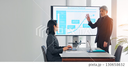 大画面モニターの前で説明するミドルエイジ男性ビジネスパーソン 130658632