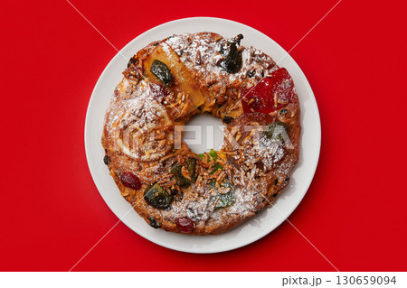 A close up of a festive cake on a white plate, surrounded by a checkered napkin and cutlery 130659094