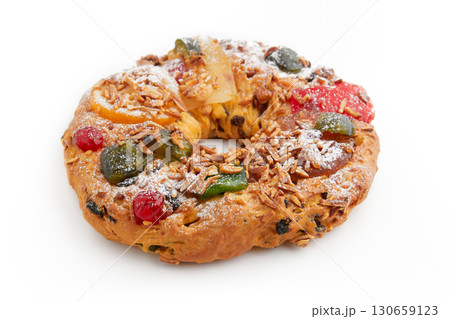 A whole round wreath-shaped cake decorated with candied cherries, nuts, and powdered sugar 130659123