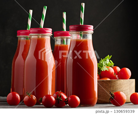 Full glass bottle with tomato juice on dark background 130659339