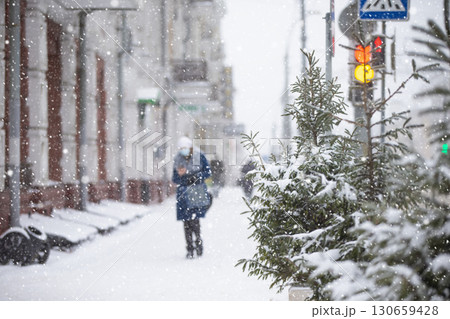 Snowfall on city streets. Blurred figure of a woman. that walks down the snowy street. Snowfall on city streets. Blurred figure of a woman. that walks down the snowy street. 130659428