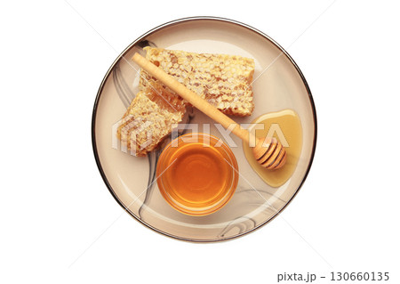 Bowl of sweet honey, dippers and combs on plate isolated on white background. Bowl of sweet honey, dippers and combs on plate isolated on white background. 130660135