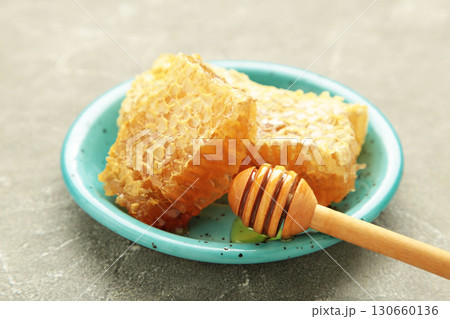 Sweet honey, dippers and combs on blue plate on grey concrete background Sweet honey, dippers and combs on blue plate on grey concrete background 130660136