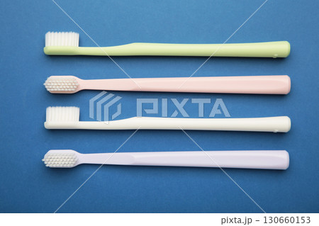 Pastel toothbrushes on dark blue background. Dental health and hygiene concept Pastel toothbrushes on dark blue background. Dental health and hygiene concept 130660153