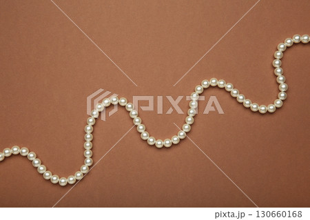Elegant pearl necklace on brown background, top view. Elegant pearl necklace on brown background, top view. 130660168