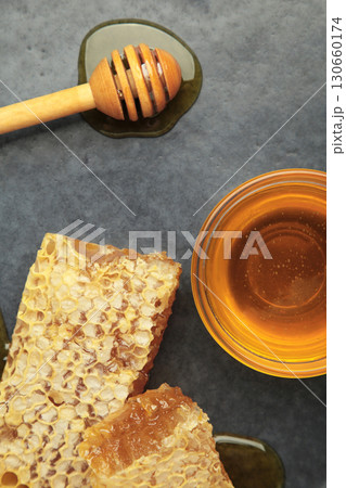 Bowl of sweet honey, dippers and combs on dark plate. Vertical photo Bowl of sweet honey, dippers and combs on dark plate. Vertical photo 130660174