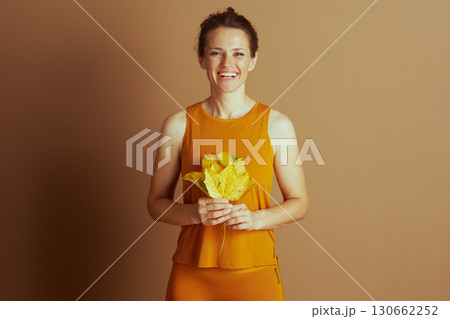 Joyful Woman with Autumn Leaves in Activewear 130662252