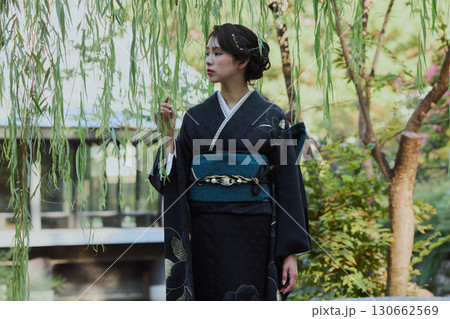 日本庭園の橋の上、柳の木の下でポーズをとる着物姿の女性｜和装・伝統美 130662569