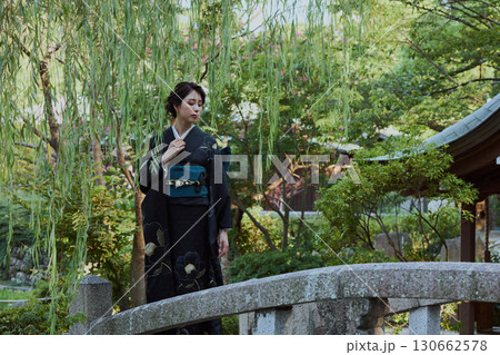 日本庭園の橋の上、柳の木の下でポーズをとる着物姿の女性｜和装・伝統美 130662578