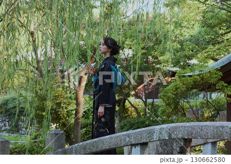 日本庭園の橋の上、柳の木の下でポーズをとる着物姿の女性|和装・伝統美 日本庭園の橋の上、柳の木の下でポーズをとる着物姿の女性|和装・伝統美 130662580
