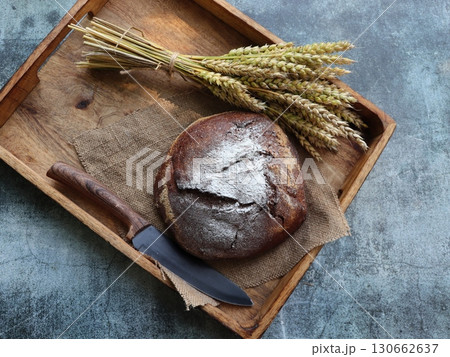 Bread background. Brown whole grain loaf on rustic dark wood desk . Baking and home bread making concept. Bread background. Brown whole grain loaf on rustic dark wood desk . Baking and home bread making concept. 130662637