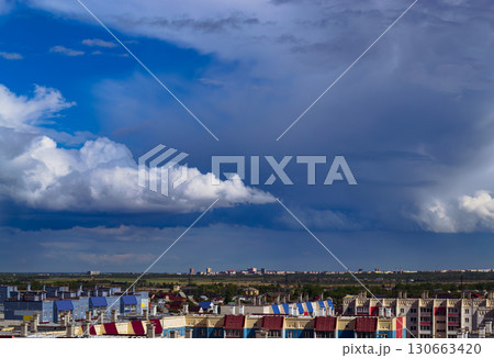A cloudy sky hangs over the roofs of houses and the city in the distance 130663420