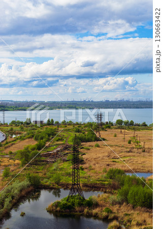 A picturesque landscape with a power line next to a lake and a beautiful cloudy sky 130663422
