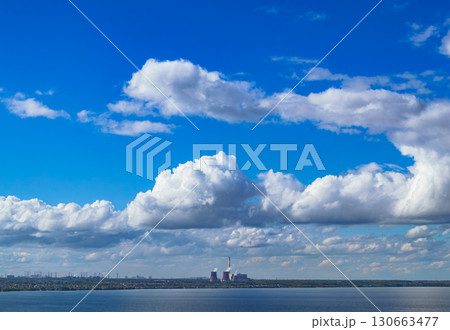 Industrial power plant by lake under blue sky 130663477