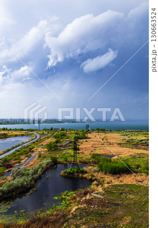 Thunderclouds over the lake and the road in the middle of the field 130663524