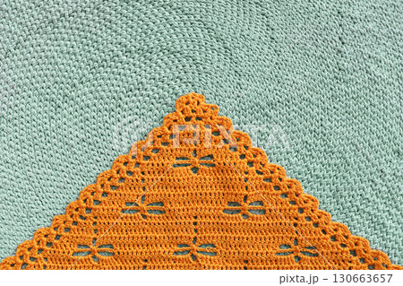 Orange crochet scarf with dragonfly pattern on green knitted background 130663657