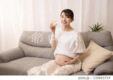 ソファーに座ってレモン水を飲む妊婦の女性 130663714