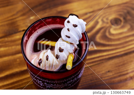 Melted marshmallow snowman in a cup of hot chocolate on wooden table 130663749