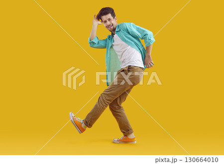 Full length portrait of dancing funky funny man in turquoise shirt on yellow background. Full length portrait of dancing funky funny man in turquoise shirt on yellow background. 130664010