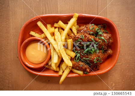 Crispy chicken wings and golden fries served with a zesty dipping sauce Crispy chicken wings and golden fries served with a zesty dipping sauce 130665543
