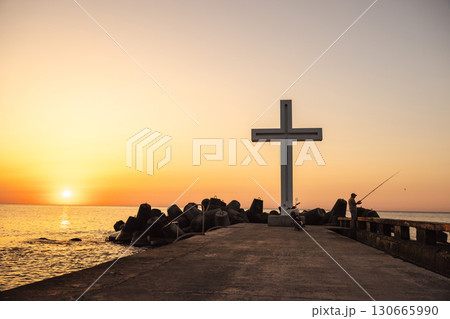 Fisherman standing near a large cross on the pier at sunset in Varna, Bulgaria Fisherman standing near a large cross on the pier at sunset in Varna, Bulgaria 130665990