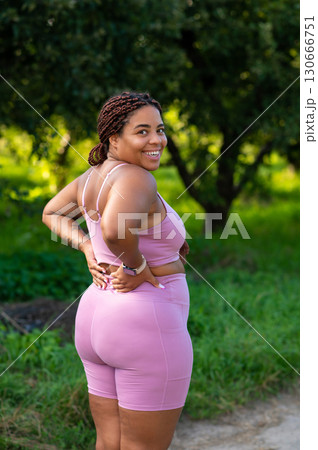 Curvy woman posing with hand on back and joyful smile over shoulder 130666751