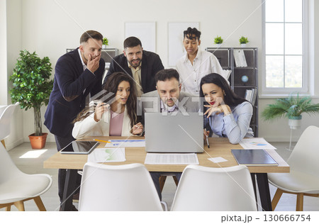 Happy gathering in office, diverse group of colleagues looking intently at laptop screen 130666754