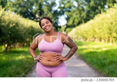 Smiling natural plus size woman in workout clothing outdoors Smiling natural plus size woman in workout clothing outdoors 130666764