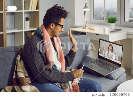 Happy man says hello to his online doctor during a consultation via a video call 130666768