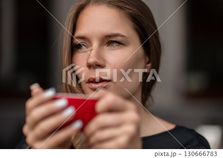Woman coffee beauty: Pensive woman holds mug indoors, likely morning, enjoying warm drink & thoughtful moment. Woman coffee beauty: Pensive woman holds mug indoors, likely morning, enjoying warm drink & thoughtful moment. 130666783