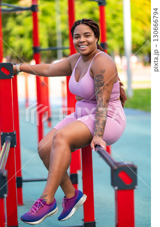 Woman with braided hair smiling in sports ground Woman with braided hair smiling in sports ground 130666794