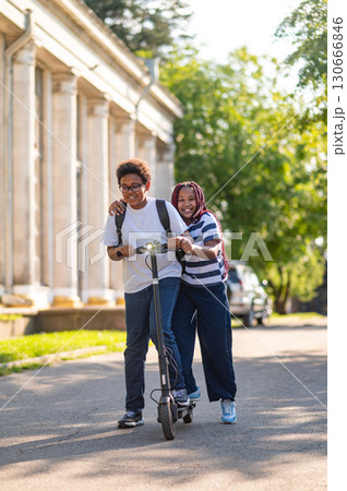 Teens enjoying a ride on a scooter and looking happy 130666846