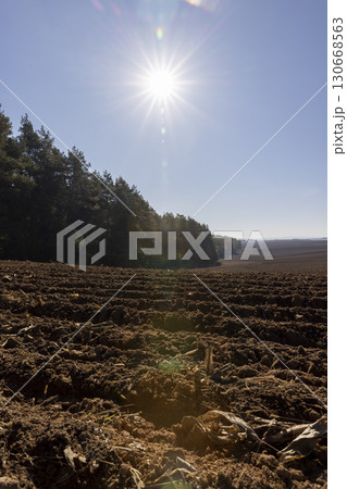 a plowed agricultural field with fertile soil prepared for sowing a new crop of plants, plowed soil in a hilly area prepared in autumn for early spring sowing 130668563