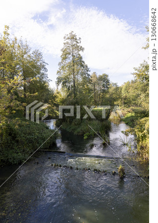 river with trees during leaf fall, a bright autumn landscape with a river and trees on the shore in the autumn season 130668642