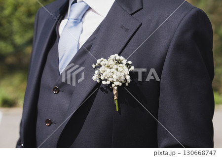 Groom with gypsophila flowers boutonniere at a wedding 130668747