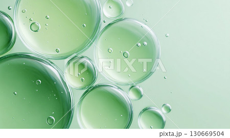 Droplets of green liquid in varying sizes create an abstract composition against a soft background showcasing light reflections and bubbles Droplets of green liquid in varying sizes create an abstract composition against a soft background showcasing light reflections and bubbles 130669504
