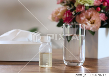 テッシュペーパー　水の入ったコップ　シロップの容器　薬を飲むイメージ　花　 130670213