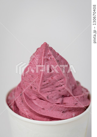 Vibrant pink berry soft serve in white cup, close-up shot on light background 130670408