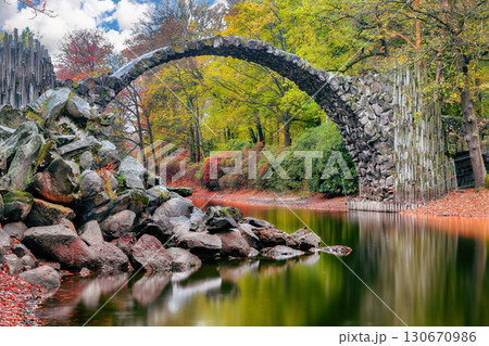 Breathtaking autumn landscape in Kromlau Rhododendron Park . Rakotz Bridge (Rakotzbrucke, Devil's Bridge) 130670986