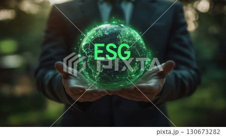 Business professional holding a glowing green globe representing environmental, social, and governance principles outdoors 130673282