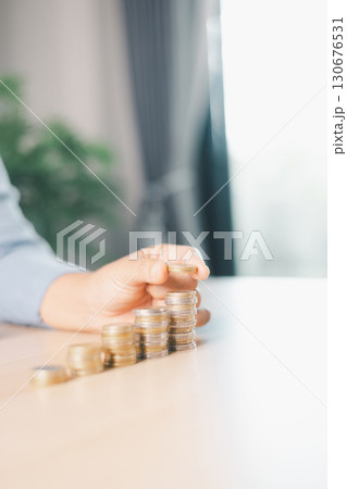 Hand places coin into saving jar, representing how smart finance, investment, banking practices turn money, cash, currency into financial wealth drives business growth and strengthens the economy. Hand places coin into saving jar, representing how smart finance, investment, banking practices turn money, cash, currency into financial wealth drives business growth and strengthens the economy. 130676531